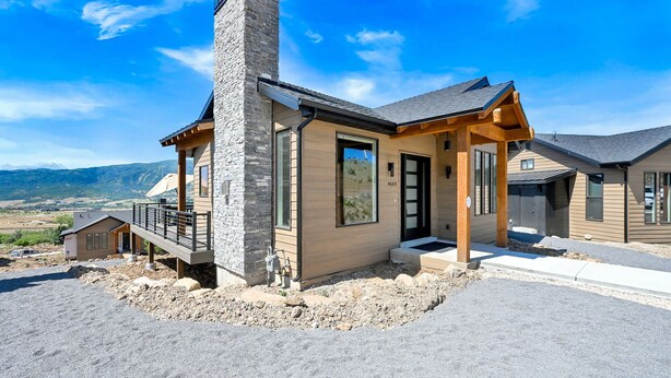 A modern house with a stone chimney, large windows, and a wooden deck. - Mountain Views Eden Cabin w/ Hot Tub & Fireplace (Eden)