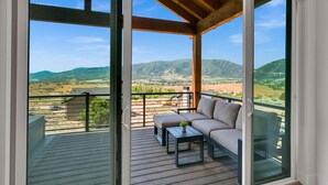 A balcony with a wooden deck, a sofa, and a small table with a plant. - Mountain Views Eden Cabin w/ Hot Tub & Fireplace (Eden)