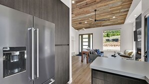 A modern kitchen with a stainless steel refrigerator, wooden ceiling, and a dining area with a view of the outdoors. - Mountain Views Eden Cabin w/ Hot Tub & Fireplace (Eden)