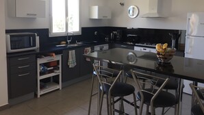 A modern kitchen with a central island, bar stools, a microwave, a refrigerator, and a window providing natural light. - Apartment in residence with swimming pool and janitor, walking distance to the beach (Zonza)