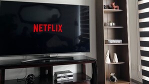 Una sala de estar moderna con un televisor de pantalla plana mostrando 'NETFLIX' y un mueble bajo de madera.
