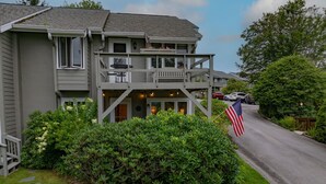 A two-story building with a balcony, a flag, and a well-maintained lawn. - Cozy Condo on the Mountain (Sugar Mountain)