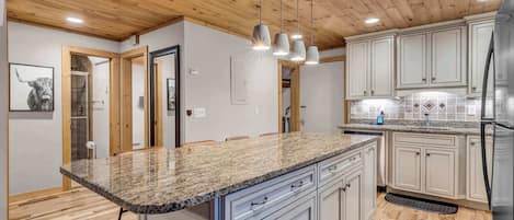 A modern kitchen with granite countertops, white cabinetry, and a stainless steel refrigerator.