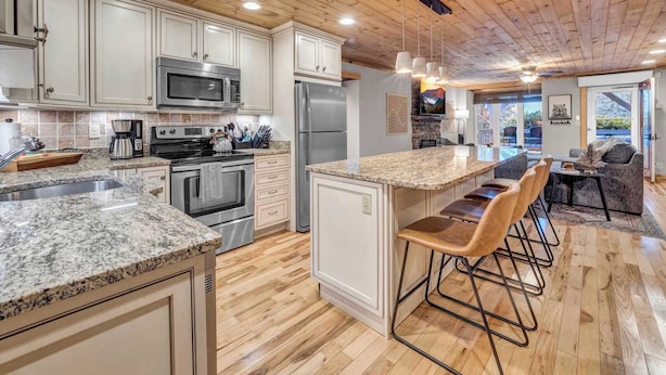 A modern kitchen with granite countertops, stainless steel appliances, and a wooden ceiling. - Cozy Condo on the Mountain (Sugar Mountain)