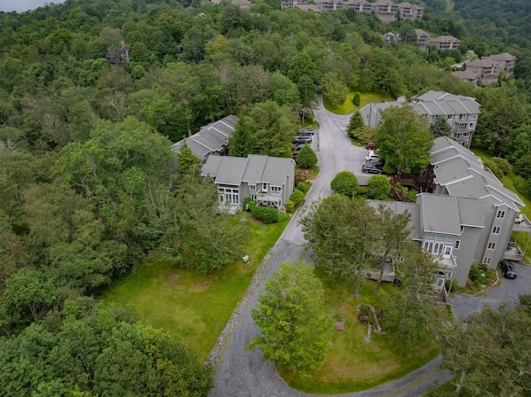 Un quartier résidentiel composé de plusieurs maisons à deux étages, une rue principale et de nombreux espaces verts environnants.