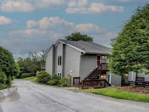 A two-story building with a grey exterior, a visible staircase, and a small porch area. - Cozy Condo on the Mountain (Sugar Mountain)
