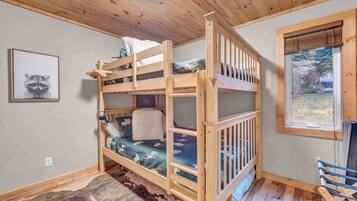 A bunk bed with a view of a forest through a window.
