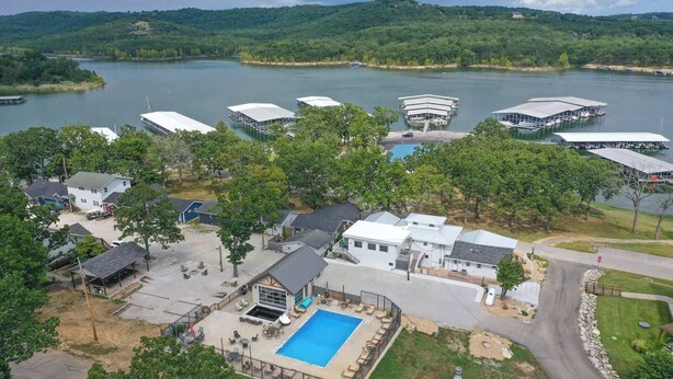 Une propriété au bord du lac, dotée d’une piscine, de bateaux amarrés et d’un petit phare.