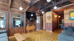 A wooden interior with a large flat-screen TV, wooden benches, and a sofa. - Panacea Boathaus Lodge - Outdoor Pool, Boat Slips (Kimberling City)