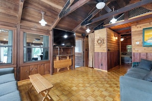 A wooden interior with a large flat-screen TV, wooden benches, and a sofa. - Panacea Boathaus Lodge - Outdoor Pool, Boat Slips (Kimberling City)