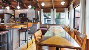 A modern kitchen with stainless steel appliances, wooden bar stools, and a large dining table with chairs. - Panacea Boathaus Lodge - Outdoor Pool, Boat Slips (Kimberling City)
