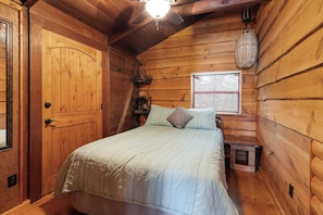 A wooden cabin bedroom with a bed, a window, a ceiling fan, and a hanging basket. - Panacea Boathaus Lodge - Outdoor Pool, Boat Slips (Kimberling City)