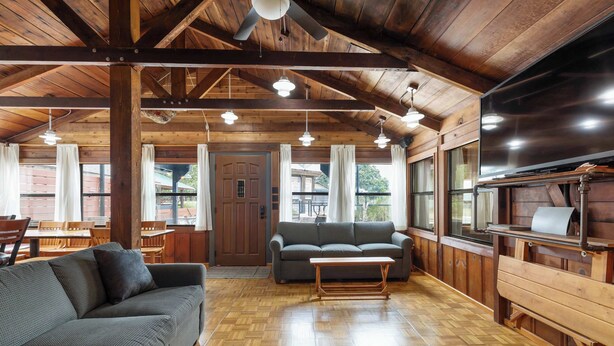 A spacious room with a wooden ceiling, a sofa, a coffee table, and a television. - Panacea Boathaus Lodge - Outdoor Pool, Boat Slips (Kimberling City)