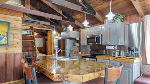A kitchen with a central island, stainless steel appliances, and wooden cabinetry. - Panacea Boathaus Lodge - Outdoor Pool, Boat Slips (Kimberling City)