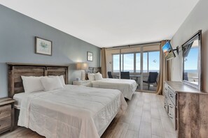 Quarto de hotel com duas camas, uma escrivaninha, cômoda e uma janela grande com vista.