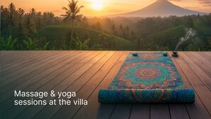 Une terrasse en bois, agrémentée d’un tapis de yoga et de pierres de méditation, offrant une vue sur un paysage luxuriant avec une montagne à l’horizon.