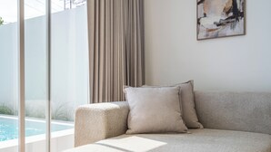 Un salon moderne avec un canapé beige, une grande fenêtre et un tableau accroché au mur.