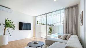 Un salon moderne avec un canapé, une table basse et un téléviseur fixé au mur.