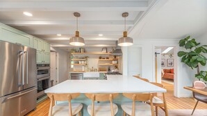 Una cocina moderna con una isla central, sillas de madera y electrodomésticos de acero inoxidable.