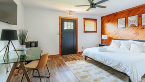 A bedroom with a bed, a desk with a chair, a television, a ceiling fan, and a wooden wall panel. - King Studio Stay in Afton w/ Desk + Private Entry (Afton)
