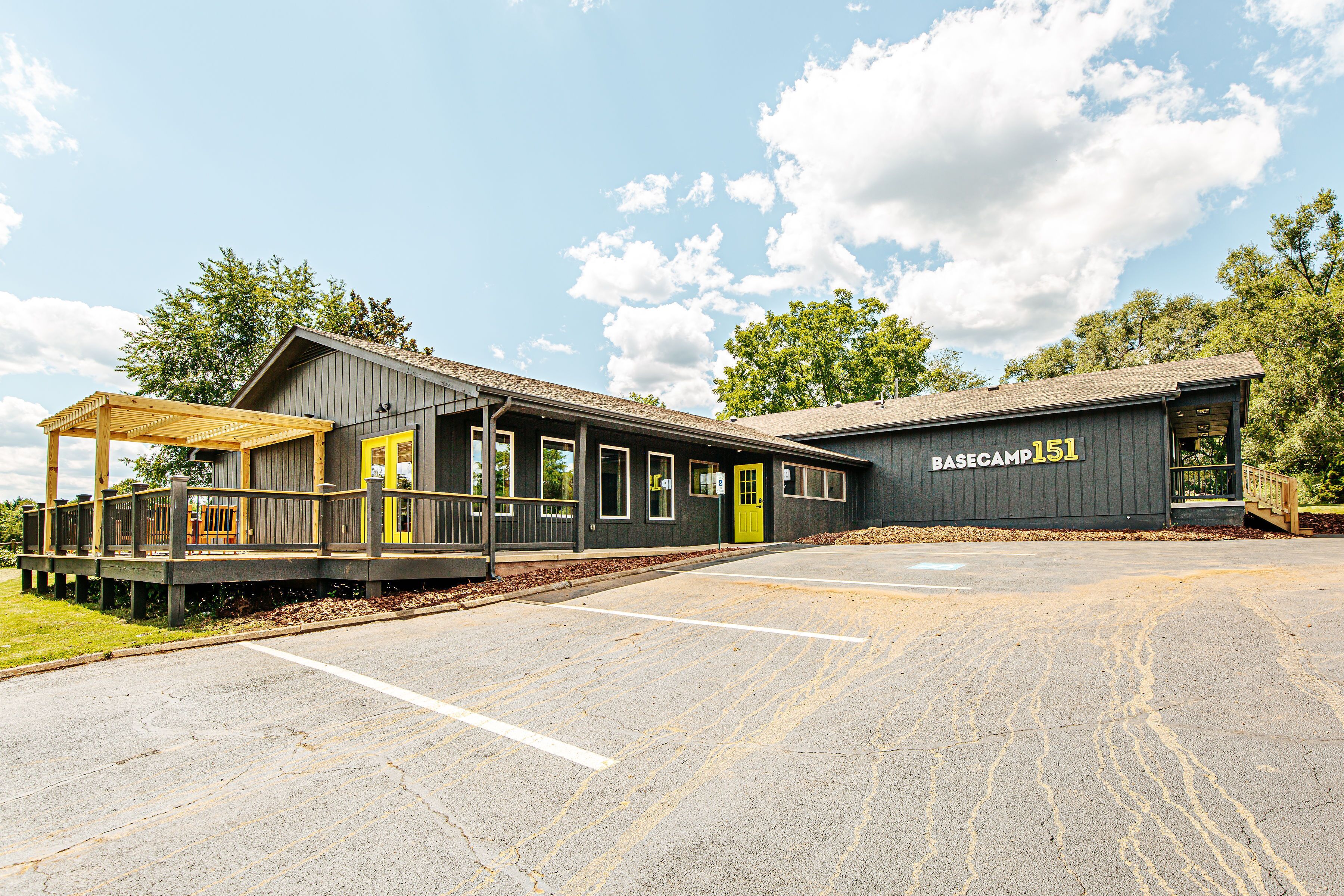 A building with a covered porch and a yellow door, labeled "BASECAMP 151".