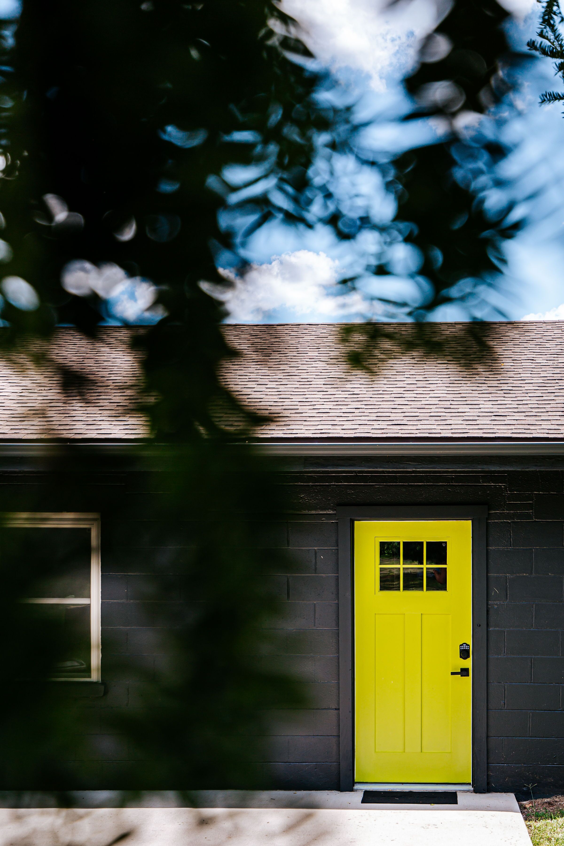 Un bâtiment avec une porte jaune vif, une fenêtre et un mur en briques.
