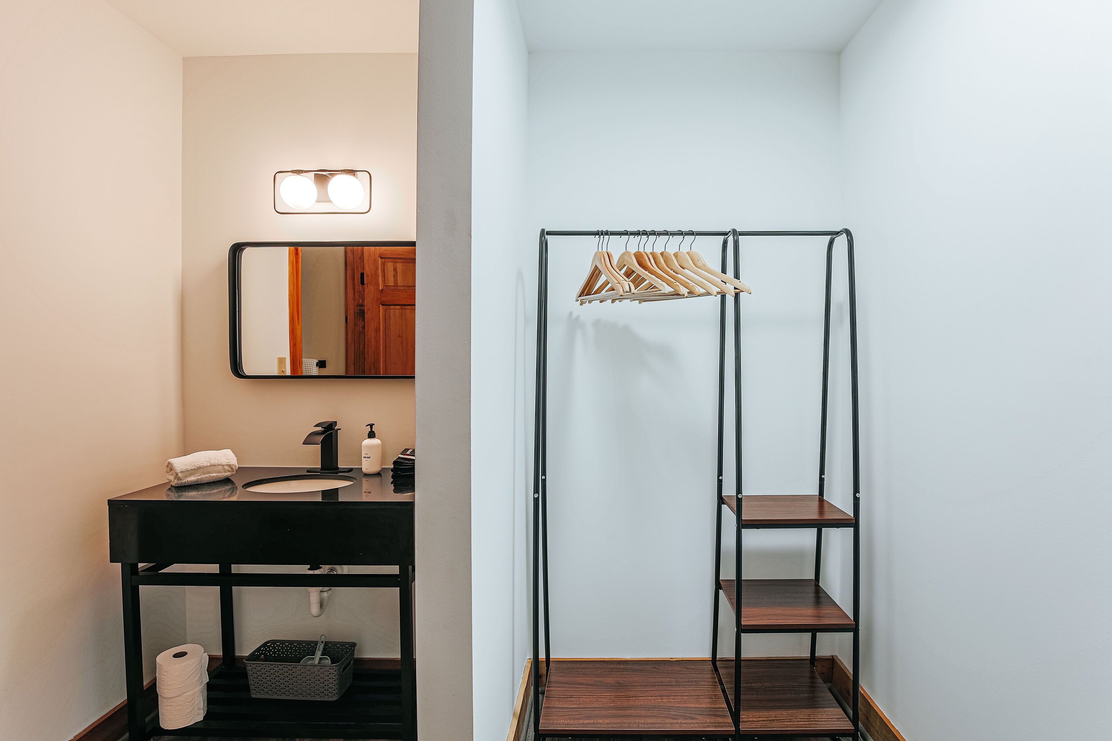 A bathroom with a black sink, mirror, and wooden shelves.