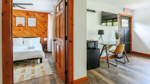 Een slaapkamer met een bed, houten lambrisering en een plafondventilator.