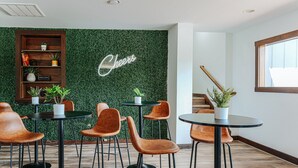 Een moderne ruimte met een verticale groenwand, een 'Cheers'-bord en verschillende tafels en stoelen.