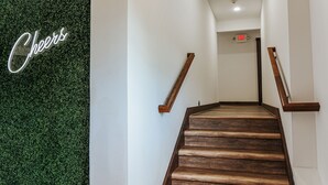 A wooden staircase with a green wall and a neon 'Cheers' sign. - Stylish Studio near Virginia Wine Trail | Sleeps 4 (Afton)