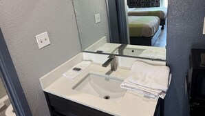 A bathroom with a white sink, a mirror, and a towel rack. - Best Value Inn Garland (Garland)