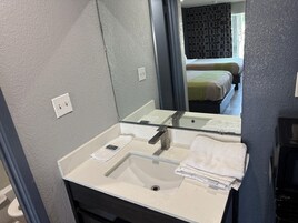 Casa de banho com lavatório branco, espelho e porta-toalhas.