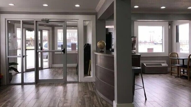 A modern interior with a kitchen area, a dining space with a table and chairs, and a large window providing natural light. - Best Value Inn Garland (Garland)