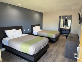 Quarto de hotel com duas camas, uma pequena escrivaninha e um espelho.