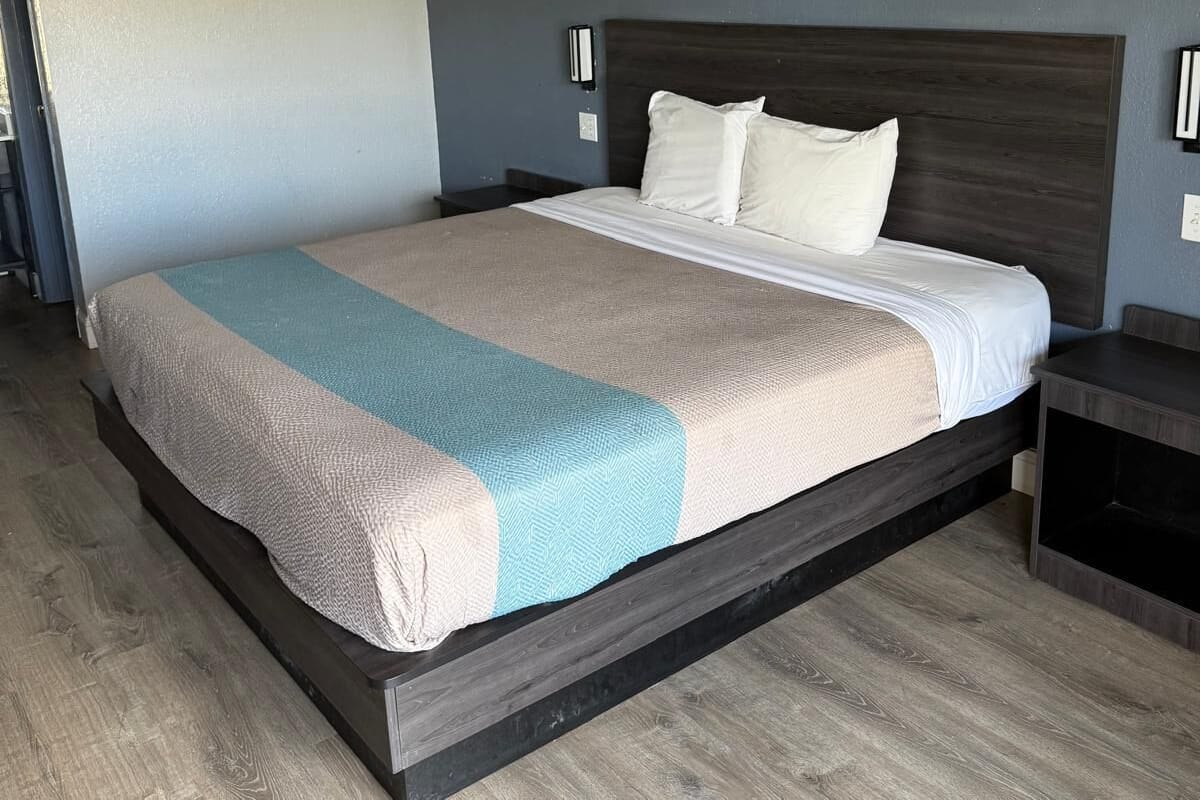 Ein modernes Schlafzimmer mit einem großen Bett, einem dunklen Holz-Kopfteil und einer hellen Wand.