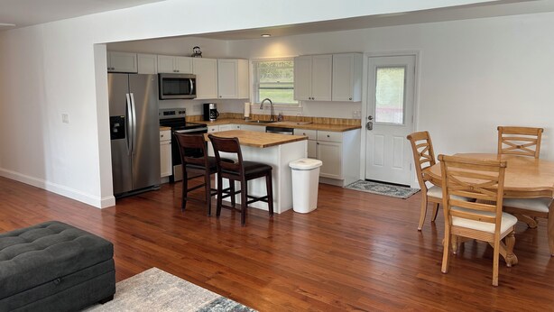 A modern kitchen with white cabinets, stainless steel appliances, and a wooden dining table with chairs.