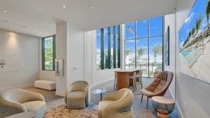 A modern hotel lobby with large windows, comfortable seating, and a view of the pool area. - New 1Bed 2bath 20th floor amazing views (Miami Beach)