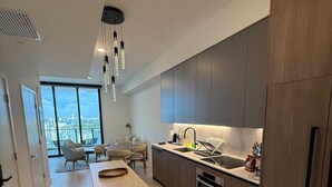 A modern kitchen with a central island, built-in appliances, and a large window offering a city view. - New 1Bed 2bath 20th floor amazing views (Miami Beach)