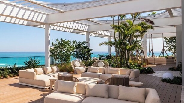 A covered outdoor lounge area with a curved ceiling, cushioned seating, and a view of the ocean. - New 1Bed 2bath 20th floor amazing views (Miami Beach)