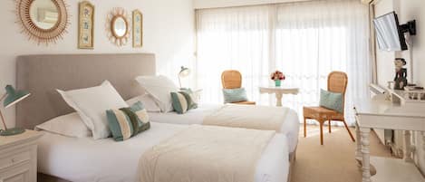 A hotel room with two beds, a desk, a chair, and a TV.