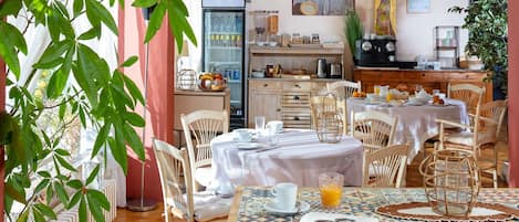 A dining area with a table set for breakfast, a refrigerator, and a kitchen area in the background.