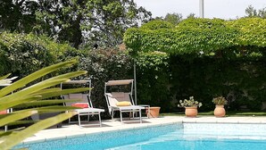 A swimming pool with two lounge chairs and two potted plants. - Hotel Le Castellan (Istres)
