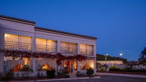A two-story building with large windows and a balcony, surrounded by greenery. - Hotel Le Castellan (Istres)