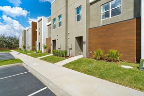 A modern building with a parking lot and a sidewalk. - Perfect Stay Just 15 Min to Disney (Davenport)