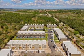 A multi-story residential building with a central courtyard, parking area, and a view of the surrounding landscape. - Perfect Stay Just 15 Min to Disney (Davenport)