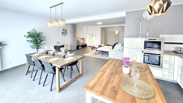A modern, open-plan living space with a dining area, kitchen, and seating area. - Well Appointed 2BR w terrace&parking (Luxembourg City)