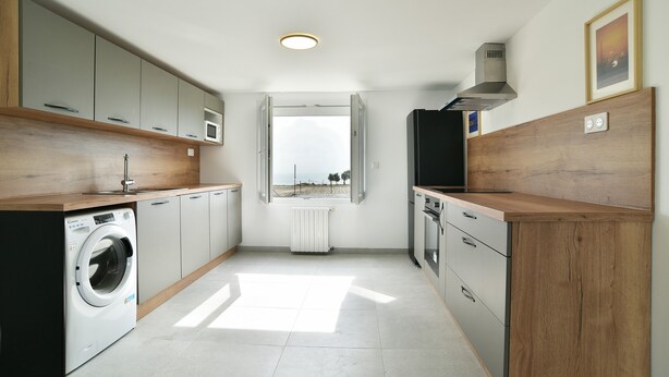 Cocina compacta con lavadora, microondas y estufa.