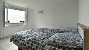 Un dormitorio con cama, ventana y un cuadro pequeño en la pared.