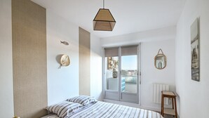Et soveværelse med en seng, en hængende lampe, et vindue og udsigt ud