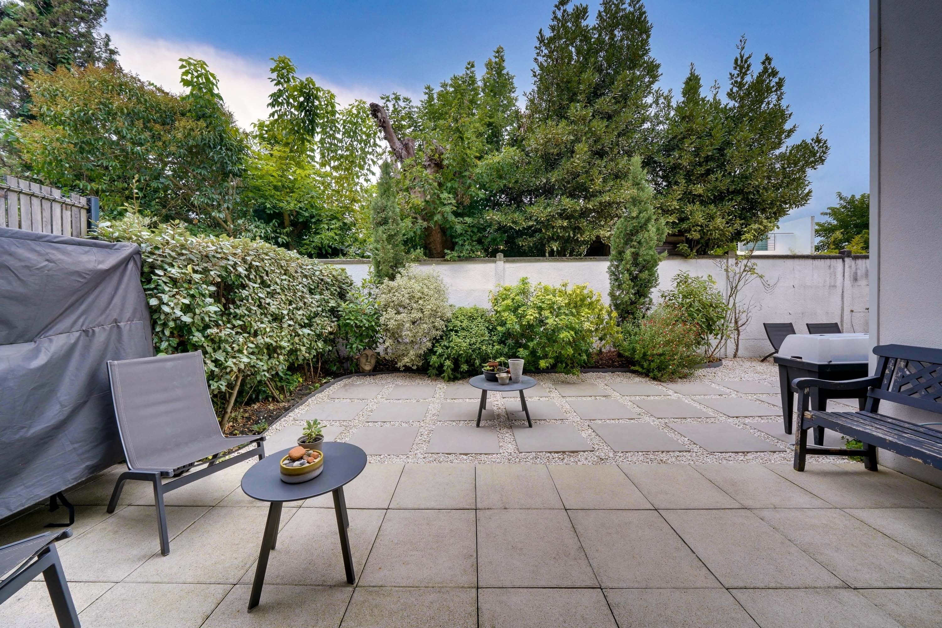 Een terras met een overdekte zithoek, een kleine tafel met een fruitschaal, en een bank.